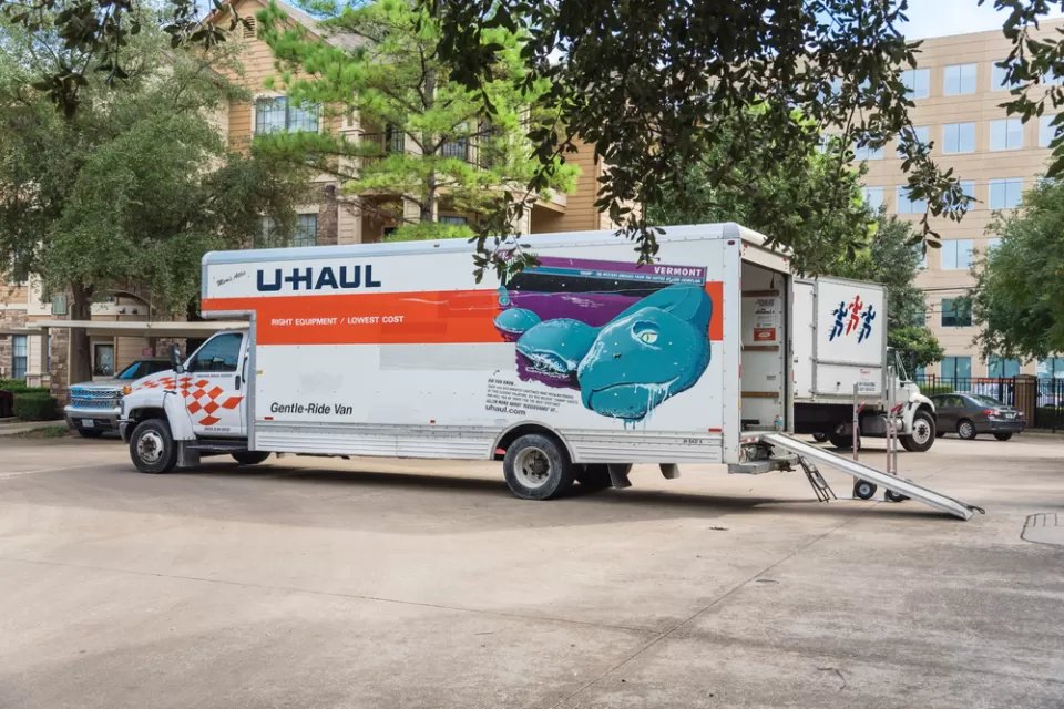 U-Haul moving truck with back door open and loading ramp down on residential street in Houston, Texas